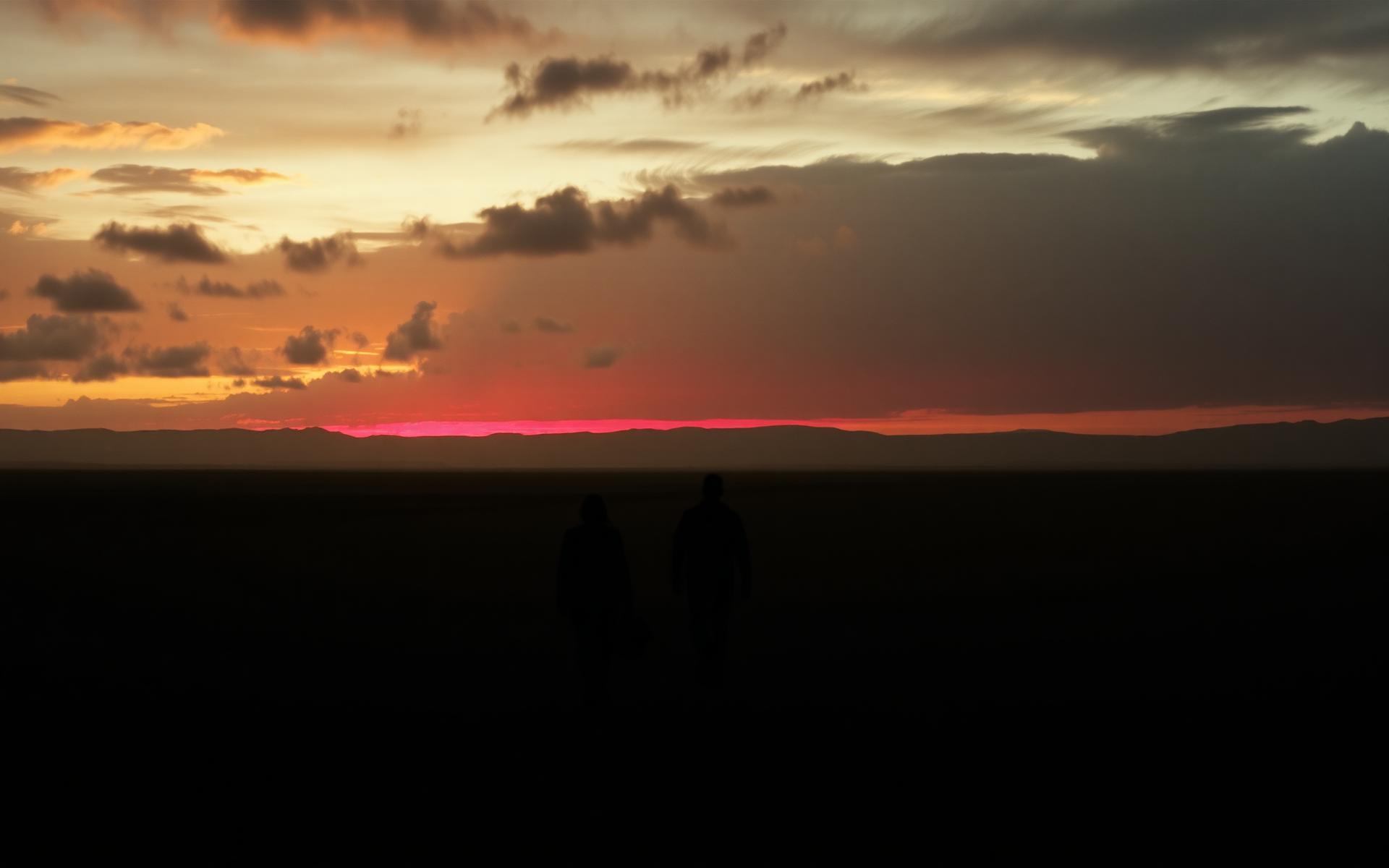 Figures walking toward the horizon at sunset