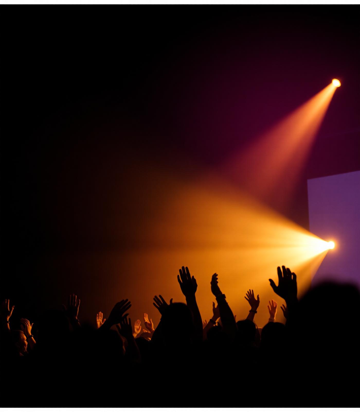 Hands raised in worship under stage light